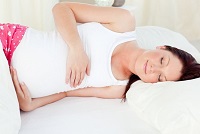 Беременная девушка лежит на боку